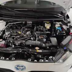 Silnik Toyoty hybrydowej z podłączonymi kablami rozruchowymi do skrzynki bezpieczników.